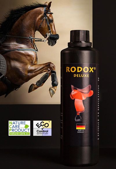 Ein brauner Hengst springt ins Bild. Im Vordergrund steht eine Flasche von RODOX® Pflege- und Reinigungsmittel für Leder-Pferdesättel. Die Überschrift lautet RODOX DELUXE. An der Seite sind zwei Labels für Nature Care Product und ECO-Control.